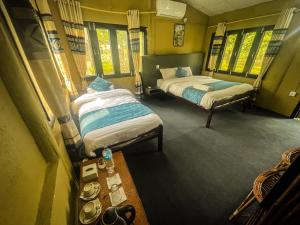 two beds in a small room with windows at Hotel Tharu Garden And Beer Bar in Chitwan