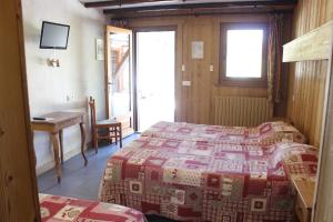 1 dormitorio con 2 camas, mesa y escritorio en Hôtel Les Bernards, en Praz-sur-Arly