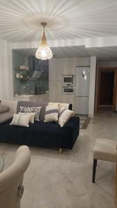 a living room with a black couch and a kitchen at ADNANIa 2023 in La Herradura