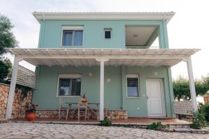 a blue house with a pergola on a patio at Villa Erato in Tsoukalades