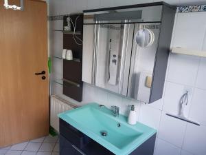 ein Badezimmer mit einem blauen Waschbecken und einem Spiegel in der Unterkunft Eneya in Rotenburg an der Fulda
