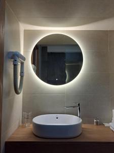 a bathroom with a sink and a round mirror at Hotel Pljevlja in Pljevlja