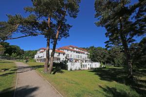 a large white building in a park with trees at Haus Meeresblick A 2.09 - Inselparadies mit Balkon in Baabe