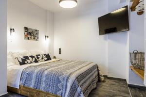 sypialnia z łóżkiem i telewizorem z płaskim ekranem w obiekcie The Grey Home w mieście Skopelos