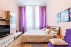 a bedroom with a bed and a tv and purple curtains at Apartment on Masaryka 39 in Karlovy Vary
