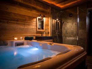 La salle de bains est pourvue d'une grande baignoire blanche et de murs en bois. dans l'établissement Venez Chez Vous - La Grange du Lac - Vue montagne, à Saint-Jorioz