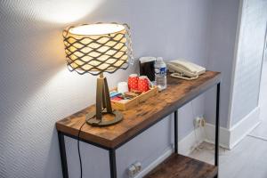 een tafel met een lamp en een telefoon erop bij Logis Hostellerie la Chaumière in Arsonval