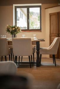 een eettafel met stoelen en een vaas met bloemen bij Venez Chez Vous - La Grange du Lac - Vue montagne in Saint-Jorioz