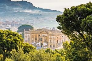 uma vista para uma mansão com árvores em primeiro plano em La Dimora di David em Bagheria