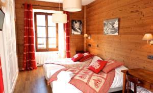 two beds in a room with wooden walls at Hôtel Viallet in Arêches