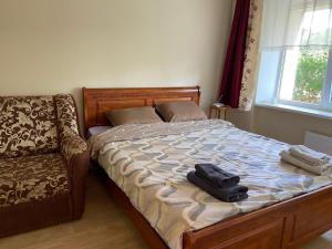 a bedroom with a bed with a chair and a suitcase on it at WILLOW apartamenti in Liepāja