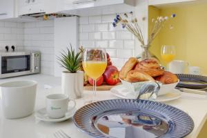 blat kuchenny ze stołem, na którym leży chleb i szklanki soku pomarańczowego w obiekcie Modern Stylish and Chic Apartment next to the Famous Paris Catacombs w Paryżu