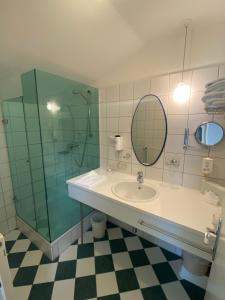 a bathroom with a sink and a shower and a mirror at Hotel Seewirt in Maria Wörth