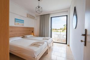 two beds in a room with a view of the ocean at Anthia Apartments in Marmari