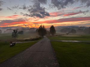 a road with a person sitting on a bench at sunset at Mid-Century DJs Dream near Rhinebeck 