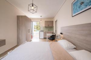 a bedroom with a large white bed and a kitchen at Anthia Apartments in Marmari