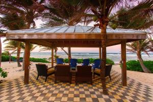 a table and chairs under a gazebo on the beach at Coconut Beach by Grand Cayman Villas & Condos in Driftwood Village