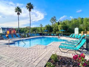 una piscina con sillas azules y palmeras en 4 Bedroom Town Home Near Disney townhouse en Kissimmee