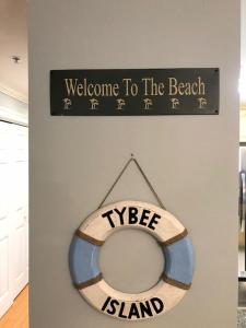 Una señal que dice bienvenido a la playa y a la tabla de aogie en Unique 3BR, 1 of 5 Condos w/Huge Poolside Patio, Steps to Beach & Pier, Gated, en Tybee Island