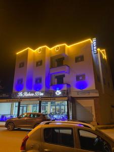 dos autos estacionados frente a un edificio por la noche en Le ruban d’or en Azilal