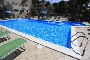 a large blue swimming pool with chairs and umbrellas at Hotel Conti in Rimini