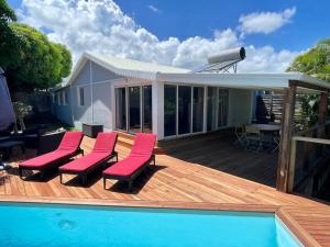 a deck with chairs and a swimming pool next to a house at Villa Bourbon de charme in Saint-Gilles les Bains