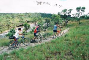 three people riding bikes on a dirt trail at Cataguás Brasil Pousada in Carrancas