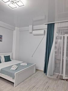 a white bedroom with a bed and a window at kato's apartment in Tbilisi City