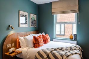 a bedroom with blue walls and a bed with orange pillows at Shepherds Bush - Your Apartment in London