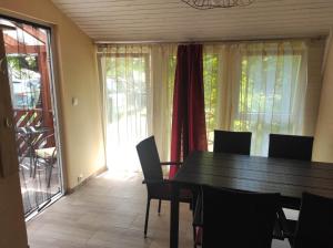 comedor con mesa, sillas y ventana en Tavasz apartman, en Balatonfenyves