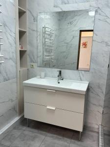 een badkamer met een witte wastafel en een spiegel bij Altair apartments Budova in Odessa