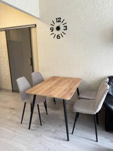 een houten tafel met stoelen en een klok aan de muur bij Altair apartments Budova in Odessa