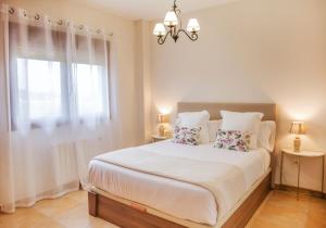 ein weißes Schlafzimmer mit einem großen Bett und einem Fenster in der Unterkunft Casa amplio jardín próximo al Parque Cabarceno in Penagos