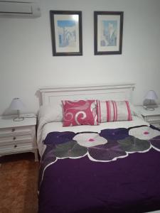 Un dormitorio con una cama con sábanas y almohadas púrpuras. en El patio de Marcos en La Recueja