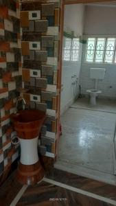een badkamer met een toilet en een muur van tegels bij Pal Bhavan in Barddhamān