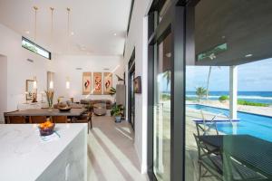 an open kitchen and dining room with a view of the ocean at Wind Upon The Waves by Grand Cayman Villas & Condos in North Side
