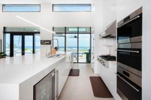a white kitchen with a view of the ocean at Wind Upon The Waves by Grand Cayman Villas & Condos in North Side
