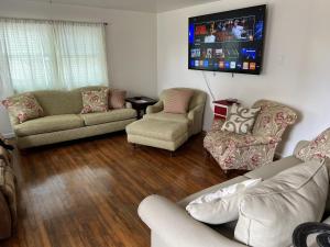Water Front Oasis home في نورفولك: غرفة معيشة مع كنب وتلفزيون بشاشة مسطحة