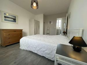 um quarto com uma cama e uma mesa com um candeeiro em Maison Saint-Martin-de-Ré, 3 pièces, 4 personnes - FR-1-246C-26 em Saint-Martin-de-Ré