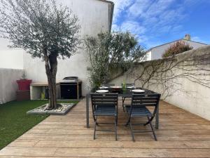 un tavolo e sedie su un patio con un albero di Maison Saint-Martin-de-Ré, 3 pièces, 4 personnes - FR-1-246C-26 a Saint-Martin-de-Ré