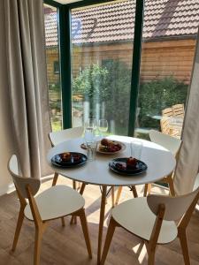 uma mesa e cadeiras com pratos e copos de vinho em Liwia Park Green House em Niechorze