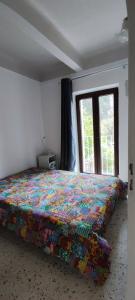 sypialnia z łóżkiem z kolorową kołdrą i oknem w obiekcie 2 Pieces indépendant Peone-Valberg w mieście Péone