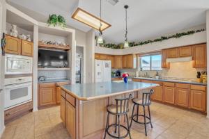 a kitchen with wooden cabinets and a large island with bar stools at Prescott Luxury Home near Golf Course and Airport home in Prescott Valley