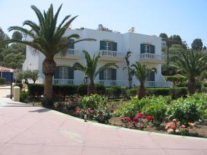 a white house with palm trees and flowers at Filoxenia Studios in Vromolithos