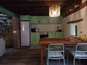eine Küche mit grünen Schränken und einem Tisch mit Stühlen in der Unterkunft Casa Pozo Tarama in Casavieja