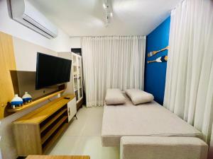uma sala de estar com uma televisão e um sofá em Village encanto - 2 quartos, luxo, térreo e lindo na Praia do Forte na Praia do Forte
