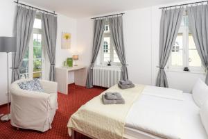 a bedroom with a bed and a chair and windows at Pension Kleine Residenz in Weimar