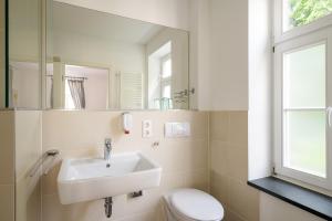 ein Badezimmer mit einem Waschbecken, einem WC und einem Spiegel in der Unterkunft Pension Kleine Residenz in Weimar