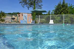 a swimming pool with blue water and an umbrella at Village de gîtes Les Olivettes in Saint-Dézéry