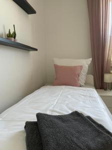 ein Schlafzimmer mit einem weißen Bett und einem rosa Kissen in der Unterkunft WH-Immobilien:Citynah mit Balkon in Hannover